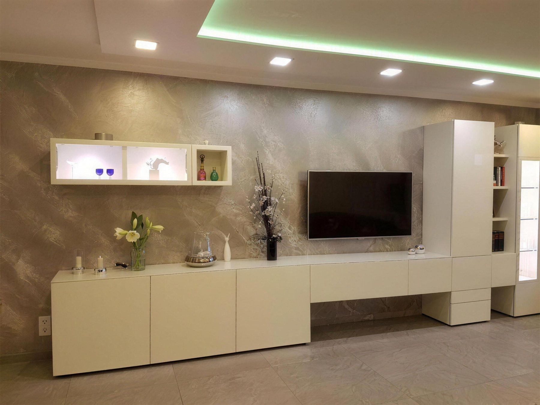Wohnzimmer mit Fernsehwand in heller Spachteltechnik und indirekter Beleuchtung